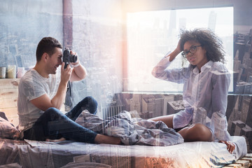 Professional photographer. Nice pleasant young man looking at his girlfriend and taking a photo while being a professional photographer