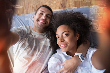 Happy moments. Joyful delighted happy couple holding a camera and smiling while taking a selfie