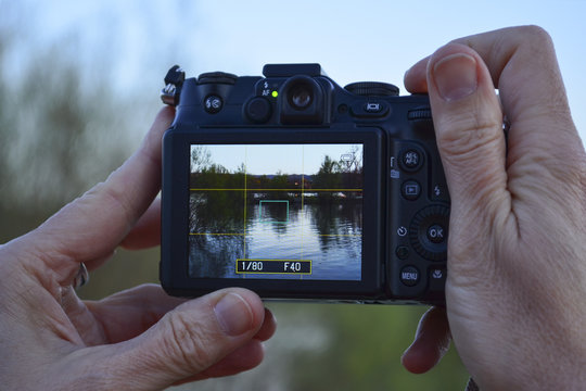 Woman's hands hold camera with lanscape on the screen taking pictures