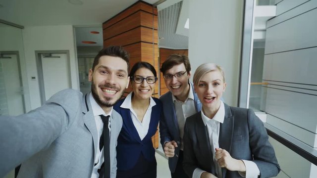 POV of Happy business team having online video chat using smartphone camera and talking to their colleague in modern office