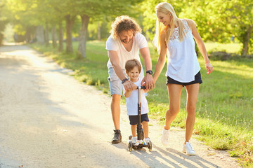 Fototapeta premium Happy family playing in the park. Mother, father and son play together in nature in the summer, in the spring.
