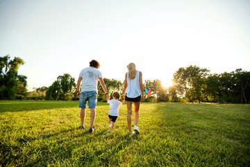 Fototapeta premium Happy family playing in the park. Mother, father and son play together in nature in the summer, in the spring.