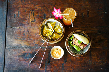Asparagus tofu dumpling and bao burger with souse. Orange drink. Top view with copy space