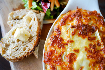 Raclette Tartiflette - french kitchen. Meat casserole on a wooden board. Close-up