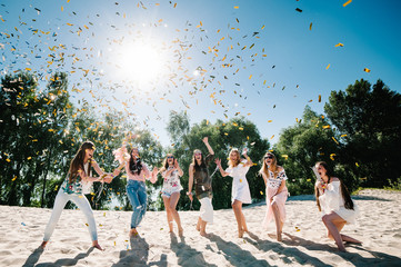 Beautiful happy stylish sexy young girls stand in beach and opens colored confetti on background nature. Party  Style boho. Maiden evening Hen-parties. Bachelorette. Close up. Portrait. Place for text