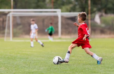 Poster Im Rahmen Boy kicking football on the sports field © Dusan Kostic