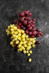 White and red bunch of grapes on a black worn background..