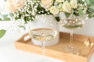 Cream wedding bouquet with roses, baby's breath and eucaluptus in wooden tray with wineglasses