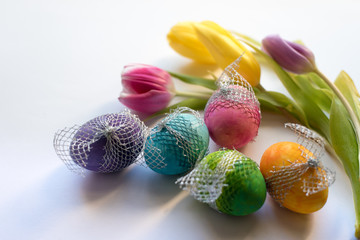 Easter Time, colorful painted eggs and spring tulips on bright background