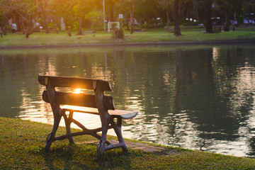 Fototapeta premium Wooden bench by a lake at sunset