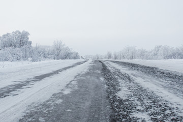 Obraz na płótnie Canvas scenic view of empty road with snow covered landscape on cloudy winter day