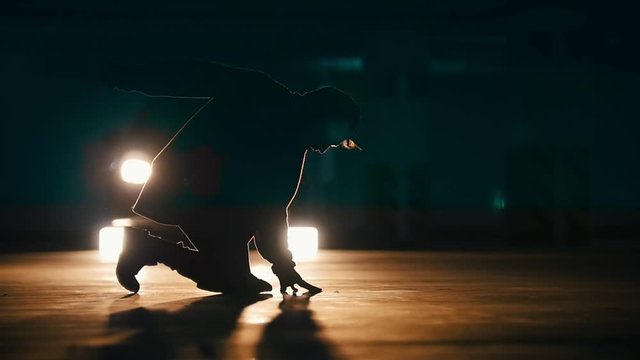 Silhouette of a young man freerunner doing acrobatic tricks on underground parking, slow motion