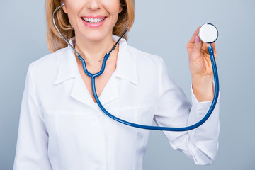 Cropped close up photo of cheerful smiling happy confident female doctor using the stethoscope,  for listening to the patient's breath, isolated on grey background