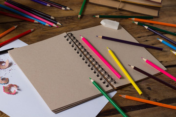 Open Notebook, Blank Paper Sheet, Colored Pencils on the Old Wooden Table