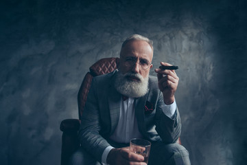 Minded, ponder rich man in glasses, hold cigarette, glass with brandy, in tuxedo with red bowtie,...