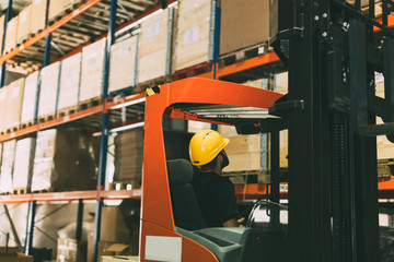 Warehouse worker doing logistics work with forklift loader © NDABCREATIVITY