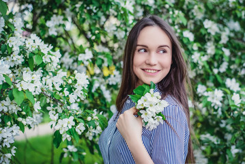 Beautiful young girl near blooming apple trees in spring