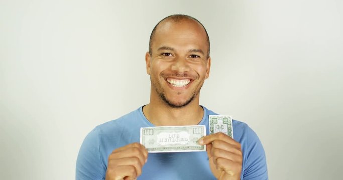 4K Extremely happy man receives unexpected cash windfall, holding note up to camera in studio shot. Slow motion.