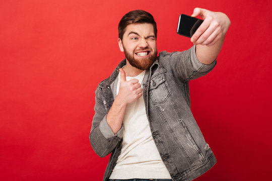 Funny man making selfie on smartphone and showing thumb up