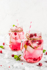 Cold summer drink, Raspberry Sangria, Lemonade or Mojito with fresh Raspberry and syrup, mint leaves, on grey stone background copy space