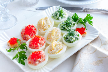 Festive serving of stuffed eggs with filling options - red, yellow, green. Selective focus, horizontal