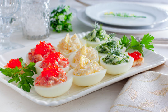 Festive serving of stuffed eggs with filling options - red, yellow, green. Selective focus, horizontal