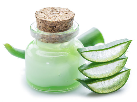 Aloe gel in the cosmetic jar and fresh aloe leaves on white background.