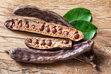 Carob pods and carob beans on the wooden table.