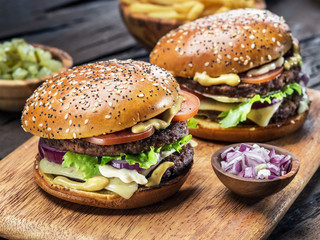 Hamburgers and French fries on the wooden tray.