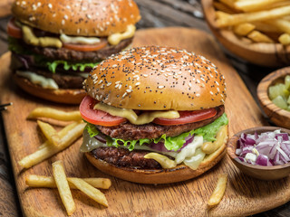 Hamburgers and French fries on the wooden tray.