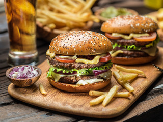 Hamburgers and French fries on the wooden tray.