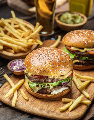 Hamburgers and French fries on the wooden tray.