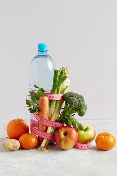 Bottle of water with a pink measuring tape, vegetables and fruit