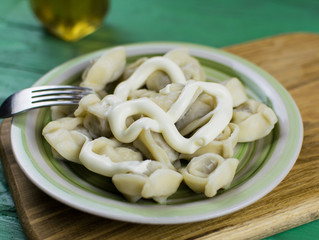 Boiled dumplings on a plate on a green wooden background.