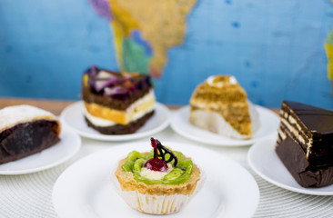 Four different cakes on white plates.