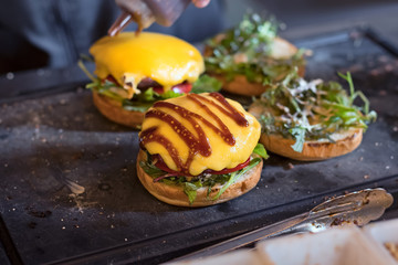 preparing burger adding the sauce on the cream cheese. Three burgers.
