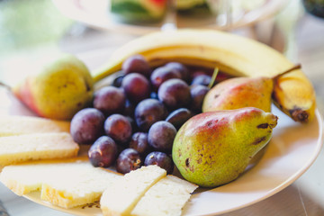Pieces of hard cheese and fruit lie on plate