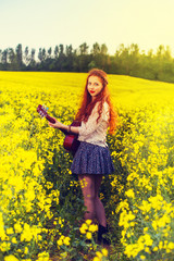 Young ginger hair girl in 70s style with acoustic guitar