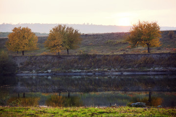 Fototapeta na wymiar autumn trees under evening sunlight reflecting in tranquil river