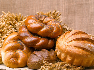 Closeup of a beautiful still-life from bread, pastry products with wheat ears, poppy seeds and buns.