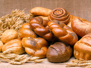 Closeup of a beautiful still-life from bread, pastry products with wheat ears, poppy seeds and buns.