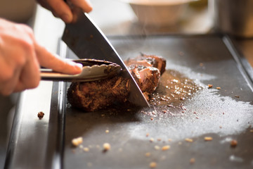 man's hands holding fork and knife cutting roast meat, Man's hands cutting meat.Close up man's hands are cutting roasted meat