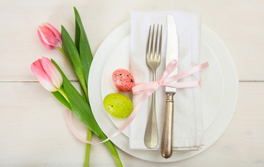 Easter table setting with pink tulips on white wooden background. Top view