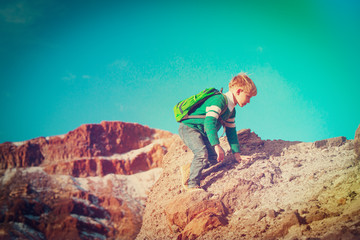 little boy with backpack hiking in mountains