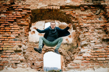 Adult crazy angry unusual excited male portrait. Businessman in flight motion. Young boy with funny comic expressive odd face emotions jumping from brick wall. Flying person. Sport activity outdoor.