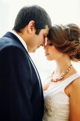 Groom and bride posing and smiling in studio for wedding shot. Wedding. Wedding day. Beautiful bride and elegant groom after wedding ceremony. 