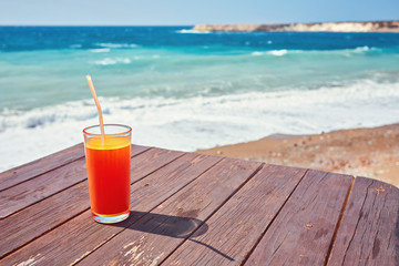 Melon juice on a sea beach. Glasses with red drink and straw stands on a fallen coconut.