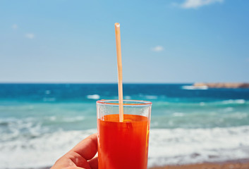 fresh drink in man's hand on the background of the exotic beach close-up