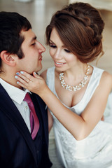 Groom and bride posing and smiling in studio for wedding shot. Wedding. Wedding day. Beautiful bride and elegant groom after wedding ceremony. 