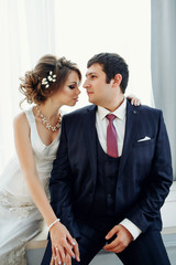 Groom and bride posing and smiling in studio for wedding shot. Wedding. Wedding day. Beautiful bride and elegant groom after wedding ceremony. 